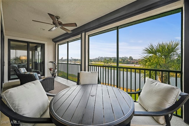 sunroom / solarium with ceiling fan and a water view