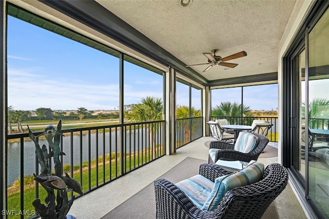 sunroom / solarium with ceiling fan and a water view