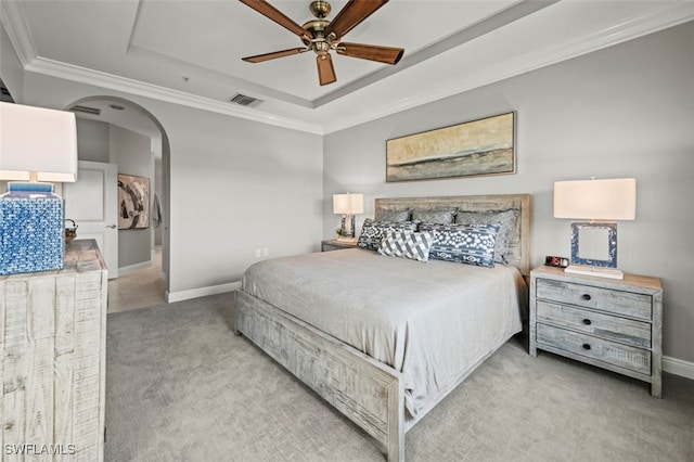 bedroom with light colored carpet, ceiling fan, a tray ceiling, and crown molding