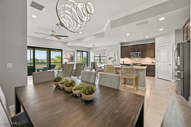 dining space featuring crown molding, ceiling fan with notable chandelier, and light tile patterned floors