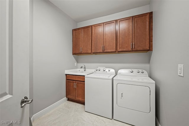 washroom with cabinets, washer and clothes dryer, and sink