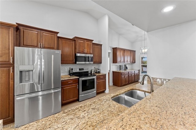 kitchen with a chandelier, a sink, appliances with stainless steel finishes, backsplash, and light stone countertops