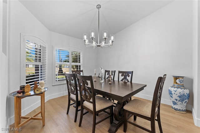 dining space featuring light wood-type flooring, baseboards, a chandelier, and vaulted ceiling