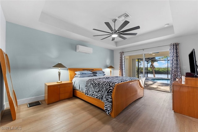 bedroom with visible vents, a tray ceiling, and an AC wall unit