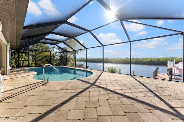 pool with glass enclosure, a patio area, and a water view