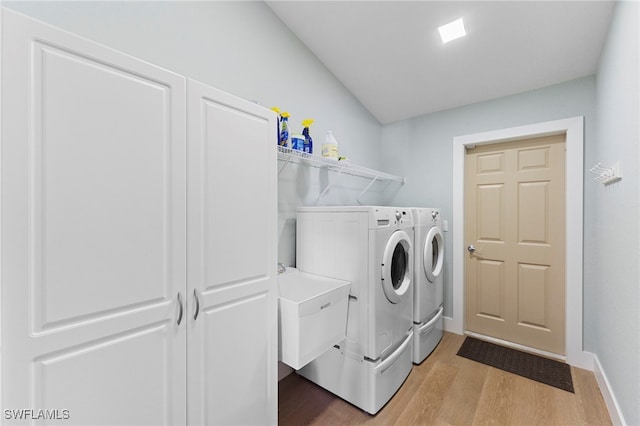 laundry area with laundry area, light wood-type flooring, washing machine and clothes dryer, and baseboards