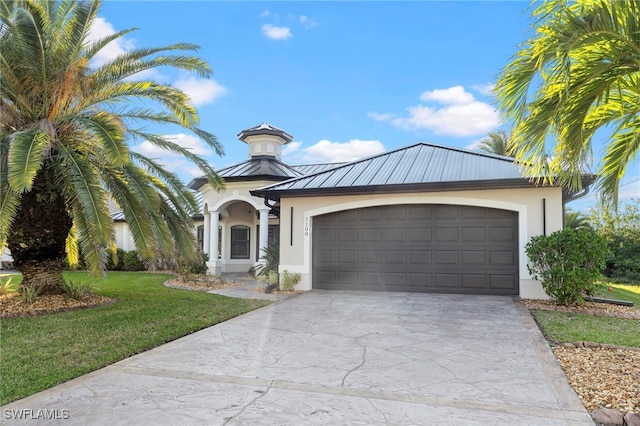 view of front of home with concrete driveway, metal roof, a front lawn, and stucco siding