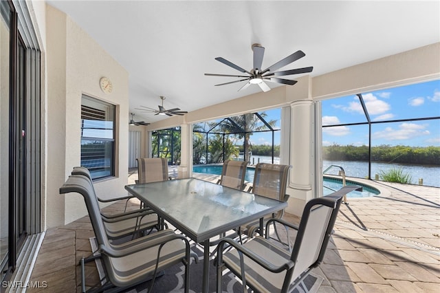 sunroom / solarium with a water view, ceiling fan, and a swimming pool