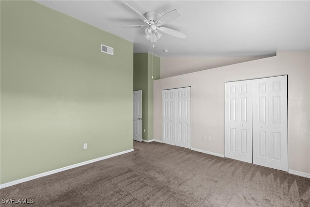 unfurnished bedroom featuring lofted ceiling, ceiling fan, carpet flooring, and multiple closets