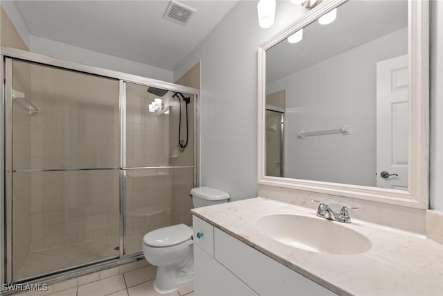 bathroom featuring vanity, toilet, tile patterned floors, and a shower with shower door