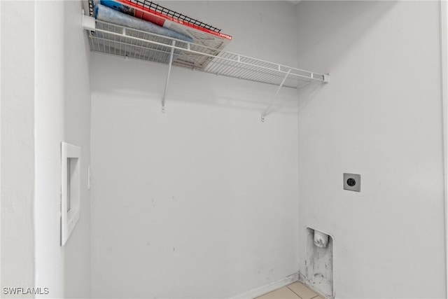 clothes washing area featuring electric dryer hookup and light tile patterned floors