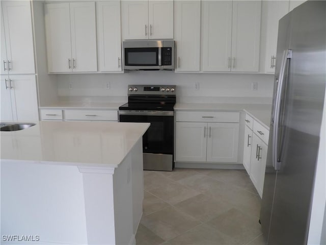 kitchen with sink, white cabinetry, appliances with stainless steel finishes, and light tile patterned flooring