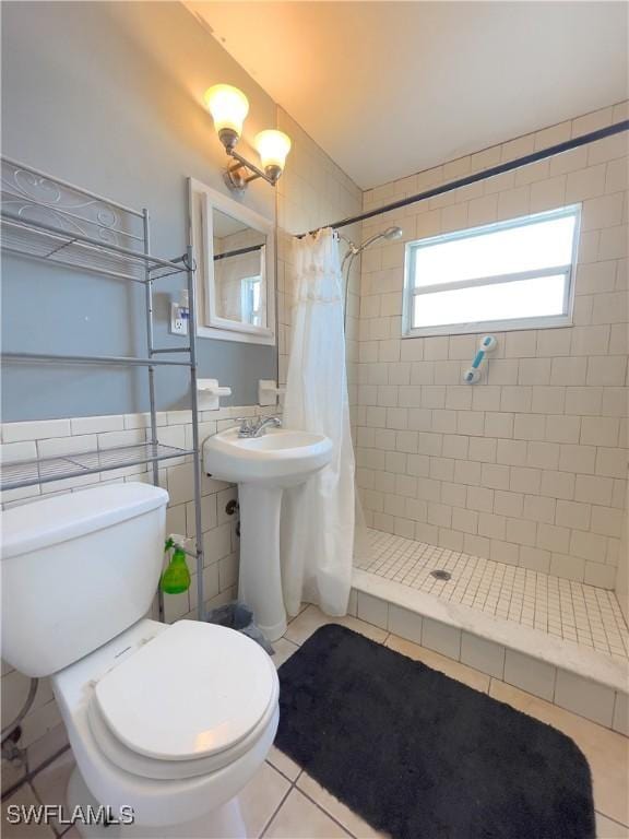 bathroom with tile walls, toilet, a shower with curtain, and tile patterned floors