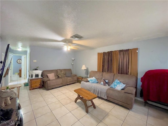 living room with a textured ceiling, ceiling fan, and light tile patterned floors