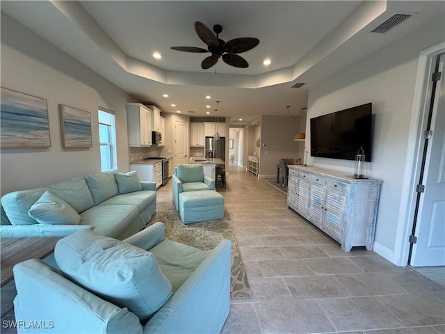 living room with ceiling fan and a tray ceiling