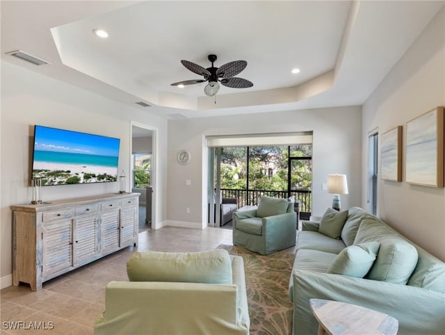 living room featuring a raised ceiling and ceiling fan