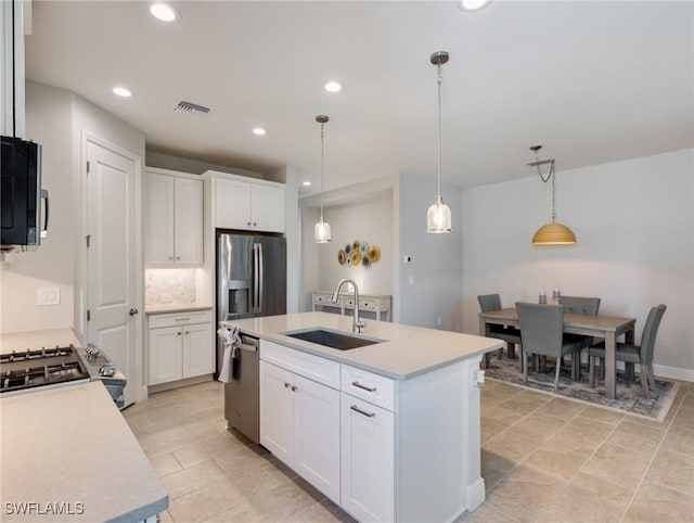 kitchen with sink, white cabinetry, pendant lighting, stainless steel appliances, and a kitchen island with sink