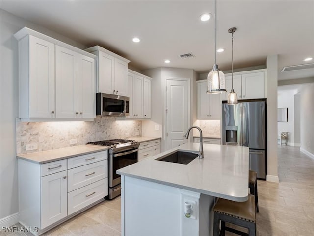 kitchen featuring stainless steel appliances, a kitchen island with sink, sink, and white cabinets