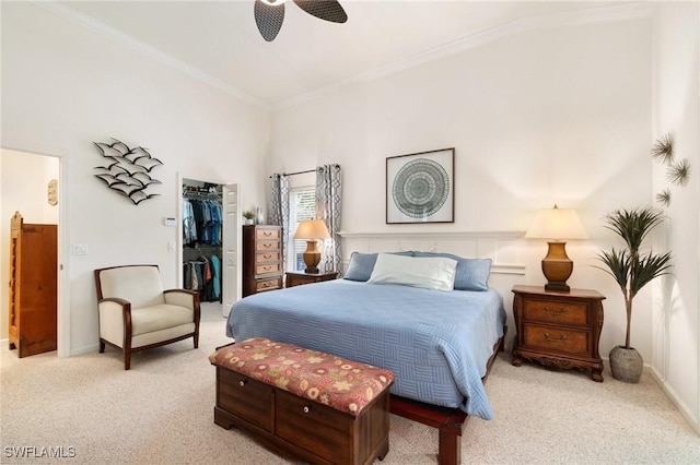 carpeted bedroom with ceiling fan, ornamental molding, a spacious closet, and a closet