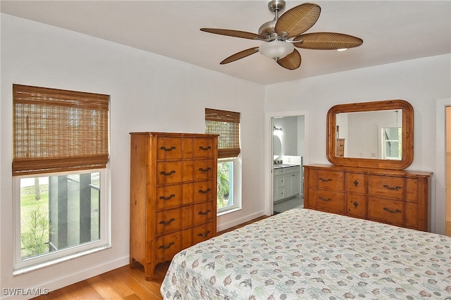 bedroom with ensuite bath, ceiling fan, and light hardwood / wood-style flooring