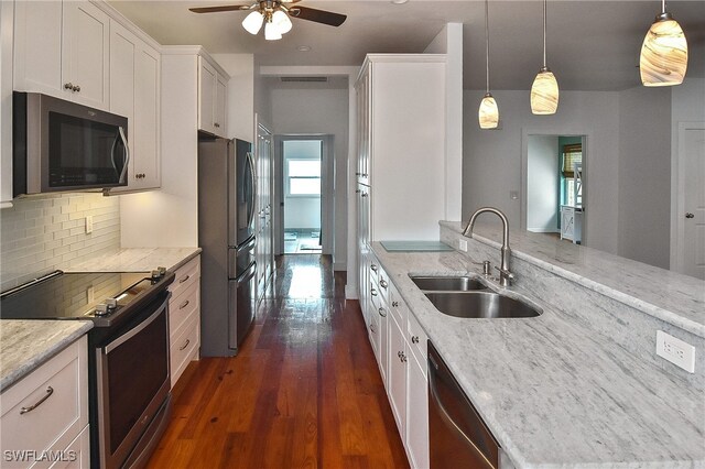 kitchen with white cabinetry, stainless steel appliances, hanging light fixtures, light stone countertops, and sink