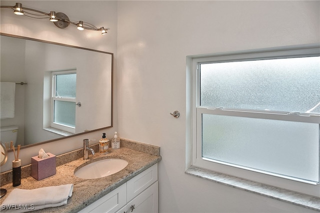 bathroom featuring toilet, vanity, and a healthy amount of sunlight