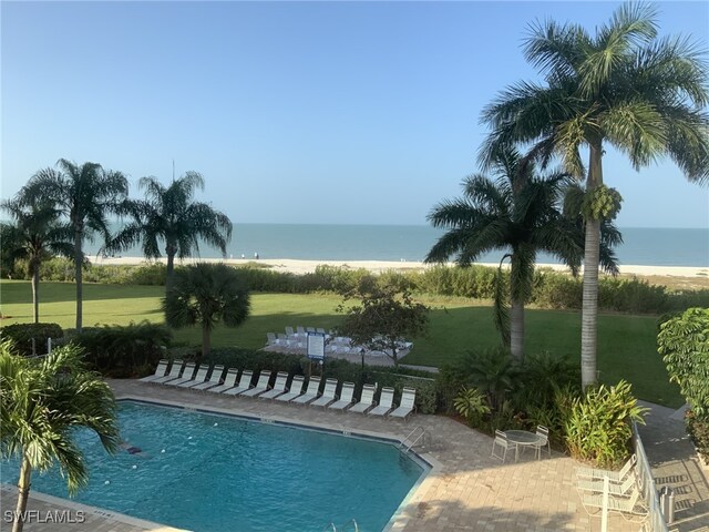 view of swimming pool featuring a yard, a water view, and a patio area