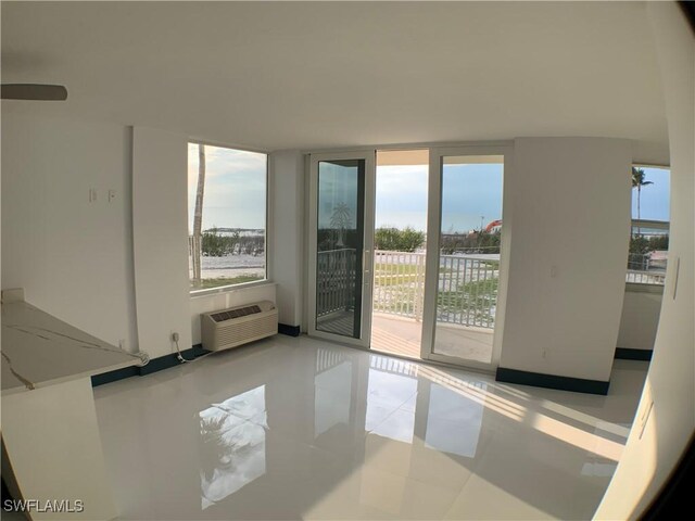 unfurnished room featuring an AC wall unit and light tile patterned floors