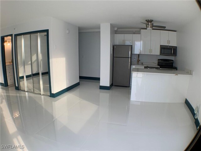 kitchen with white cabinets, stainless steel appliances, light tile patterned floors, and ceiling fan