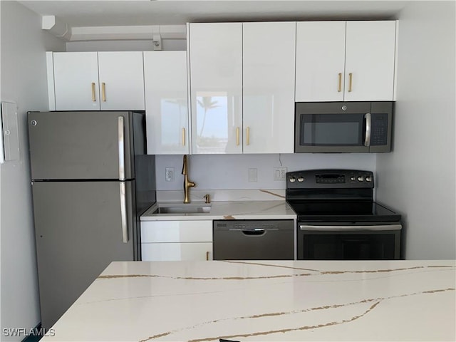 kitchen featuring light stone counters, white cabinets, sink, and black appliances