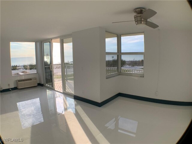 unfurnished room with a healthy amount of sunlight, ceiling fan, tile patterned flooring, and an AC wall unit