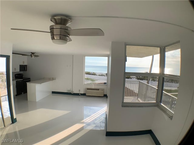 interior space with a wall mounted AC, ceiling fan, a healthy amount of sunlight, and a water view