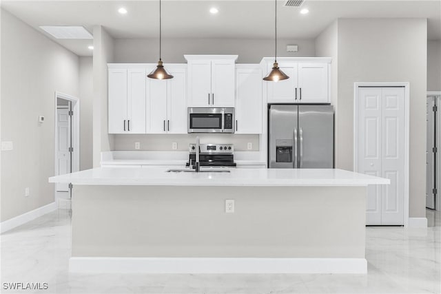 kitchen featuring white cabinets, pendant lighting, an island with sink, and appliances with stainless steel finishes