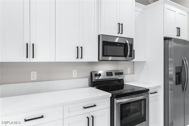 kitchen with appliances with stainless steel finishes, white cabinetry, and light stone counters