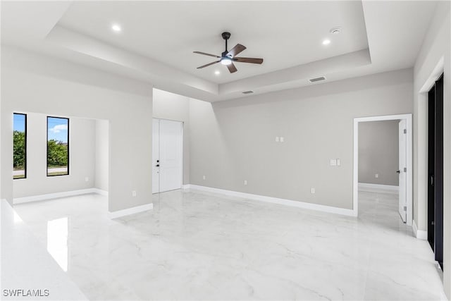 spare room with ceiling fan and a tray ceiling