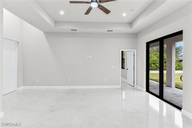 unfurnished room with ceiling fan and a tray ceiling