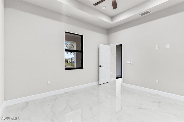 empty room featuring a raised ceiling and ceiling fan