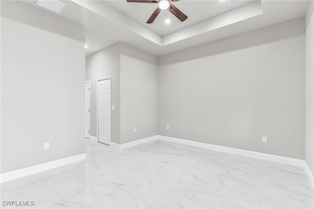 empty room with a raised ceiling and ceiling fan