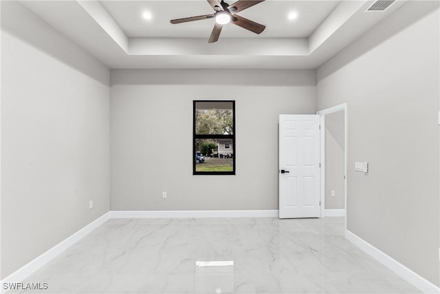 empty room featuring ceiling fan and a raised ceiling