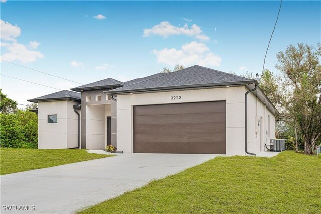 view of front of home featuring central air condition unit, a front yard, and a garage