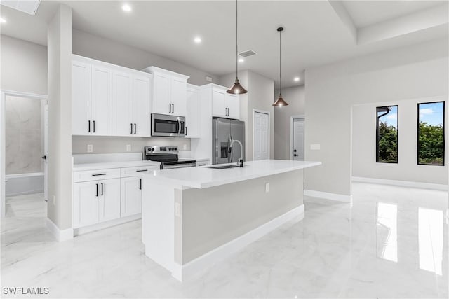 kitchen with pendant lighting, stainless steel appliances, an island with sink, white cabinetry, and sink