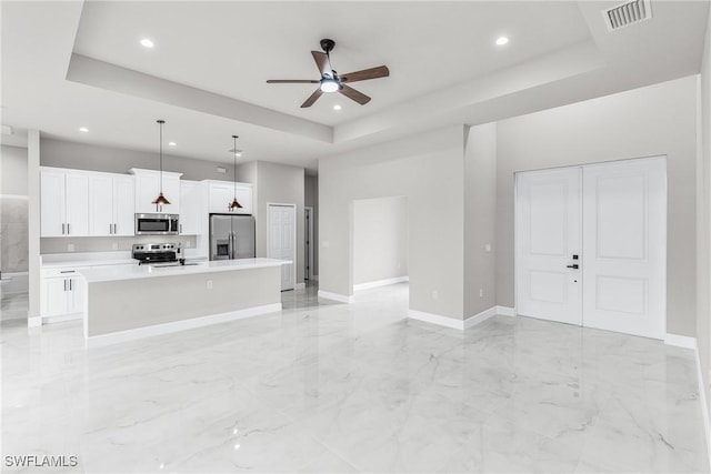 unfurnished living room with ceiling fan, a tray ceiling, and sink