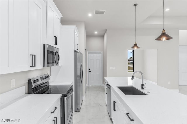 kitchen featuring appliances with stainless steel finishes, white cabinetry, pendant lighting, and sink