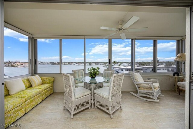 sunroom / solarium with ceiling fan and a water view