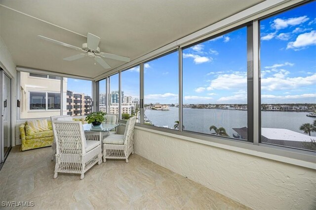 sunroom / solarium featuring ceiling fan and a water view