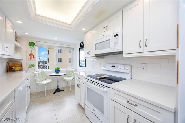 kitchen with white appliances, crown molding, a tray ceiling, white cabinets, and decorative backsplash