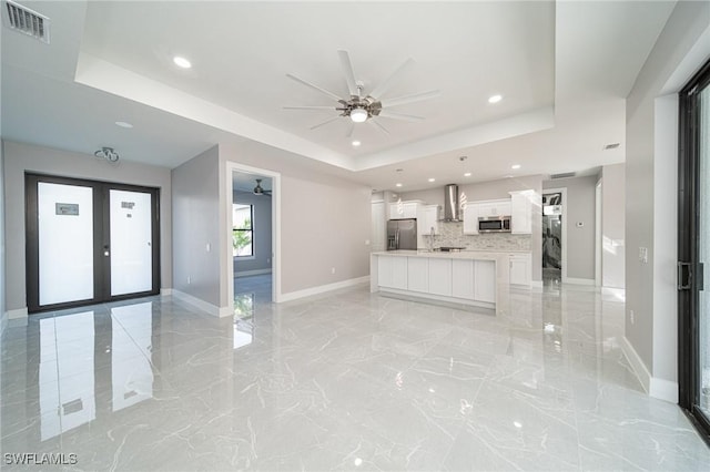 unfurnished living room featuring french doors, ceiling fan, and a tray ceiling