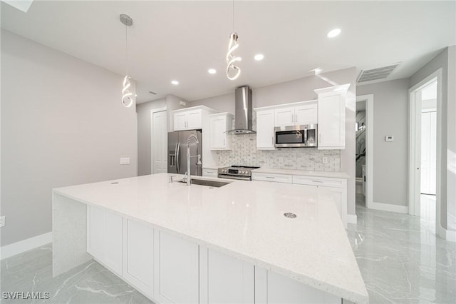 kitchen featuring appliances with stainless steel finishes, decorative light fixtures, white cabinets, a large island, and wall chimney exhaust hood