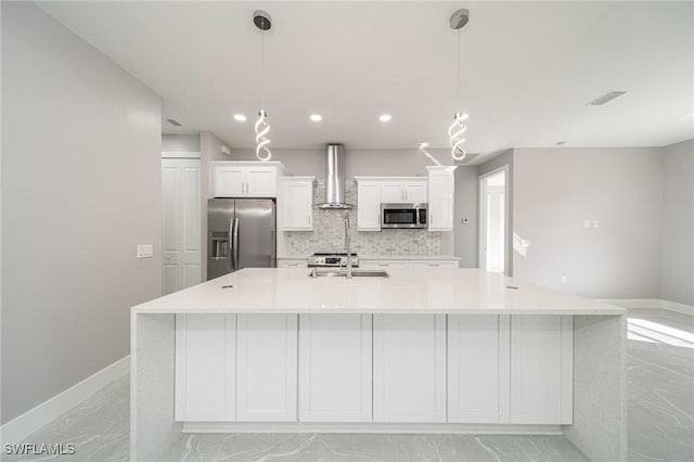 kitchen featuring pendant lighting, wall chimney range hood, white cabinets, and appliances with stainless steel finishes