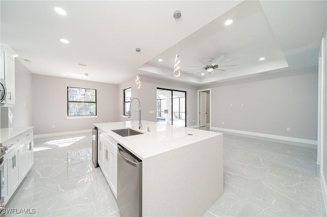 kitchen with sink, appliances with stainless steel finishes, a tray ceiling, a kitchen island with sink, and white cabinets